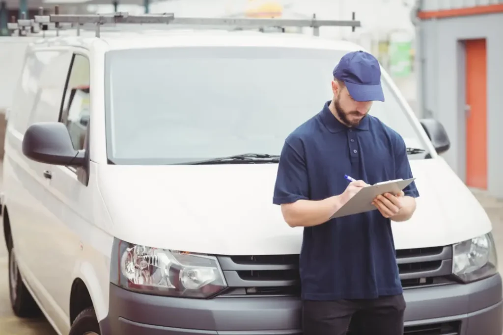 Man inspecting a white van and taking notes on a clipboard, emphasizing pre-sale checks for condition assessment.